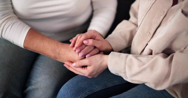 A woman holds an elderly family member’s hands while offering emotional support. (Shutterstock Photo) 