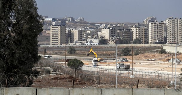 A general view shows a section of Israel's controversial separation wall (bottom) and machinery working on the tarmac of the former Atarot airport (Jerusalem International Airport), which has been closed to civilian traffic since the breakout of the second Palestinian intifada (uprising) in 2000, near the village of Qalandia between the West Bank city of Ramallah and Israel-annexed east Jerusalem, Nov. 25, 2021. (AFP Photo)