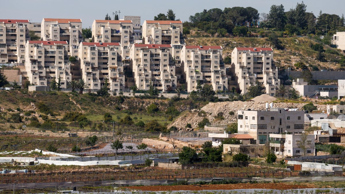 The illegal Kiryat Arba settlement appears in the background near Palestinian houses adjacent to road 60, near Hebron, in the Israeli-occupied West Bank, May 7, 2026. (Reuters Photo)