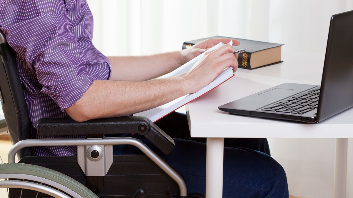 A man in a wheelchair works at his desk. (Shutterstock Photo) 
