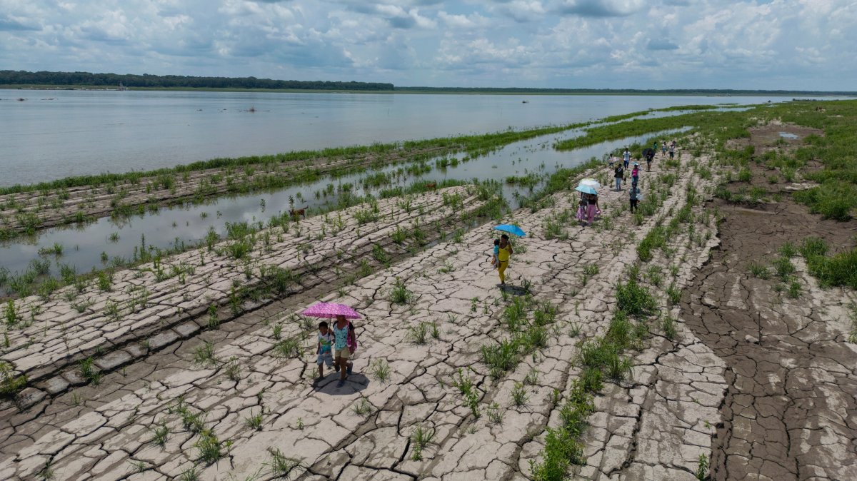 People walk through a part of the Amazon River that shows signs of drought in Santa Sofia, on the outskirts of Leticia, Colombia, Oct. 20, 2024. (AP Photo)