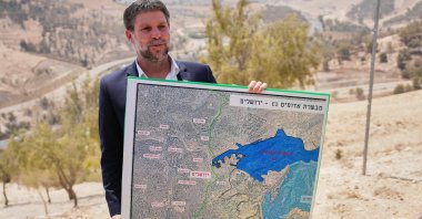 Israeli Finance Minister Bezalel Smotrich holds a map that shows the E1 settlement project during a press conference near the settlement of Maale Adumim, Israeli-occupied West Bank, Palestine, Aug. 14, 2025. (AP Photo)