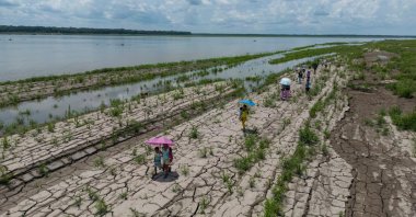 People walk through a part of the Amazon River that shows signs of drought in Santa Sofia, on the outskirts of Leticia, Colombia, Oct. 20, 2024. (AP Photo)