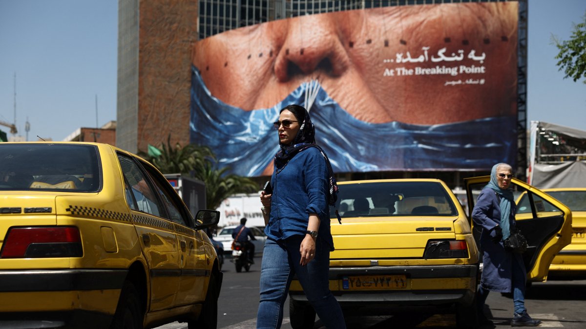 A woman walks past an anti-U.S. billboard depicting U.S. President Donald Trump and the Strait of Hormuz, Tehran, Iran, May 11, 2026. (Reuters Photo)