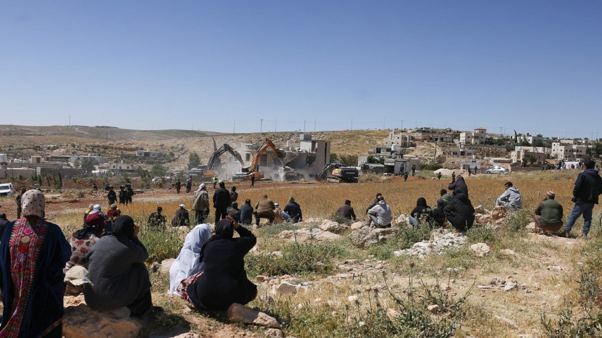 Palestinians watch as Israeli security forces stand guard while excavators demolish a Palestinian house in the village of al-Dirat near Yatta town in Hebron, occupied West Bank, May 4, 2026. (AFP Photo)