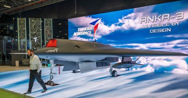 A man walks past an Anka-3, Türkiye's first flying-wing, deep-strike stealth unmanned fighter jet, manufactured by Turkish Aerospace Industries (TAI) during the opening day of SAHA 2026, an international defense and aerospace exhibition, Istanbul, Türkiye, May 5, 2026. (AFP Photo)