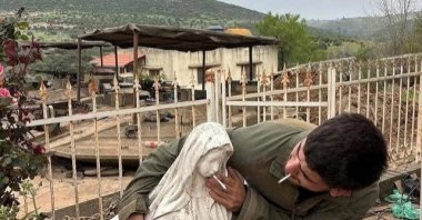 A soldier smokes and pushes another cigarette onto the mouth of a statue of the Virgin Mary in Debel, Lebanon, in this picture released May 6, 2026, obtained from social media. (Reuters Photo)