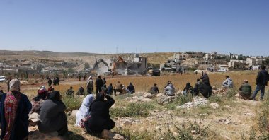 Palestinians watch as Israeli security forces stand guard while excavators demolish a Palestinian house in the village of al-Dirat near Yatta town in Hebron, occupied West Bank, May 4, 2026. (AFP Photo)