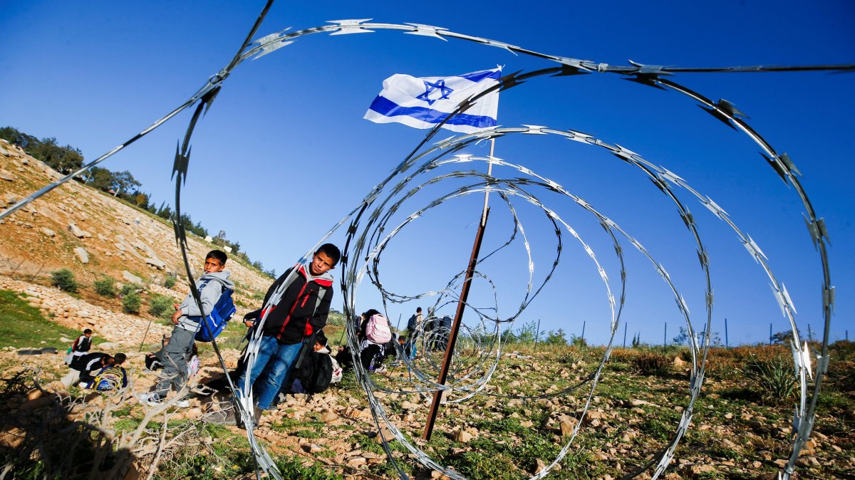 Palestinian students gather near a fence installed by Israeli settlers in their way to school, near Umm al-Khair village in Masafer Yatta, in the Israeli-occupied West Bank, Palestine, April 14, 2026. (Reuters Photo)