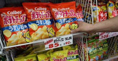 A staff member adds stock of Calbee potato chips to a shelf at a confectionery speciality store, Tokyo, Japan, May 12, 2026. (Reuters Photo)