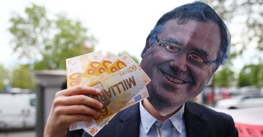 An activist wearing a mask depicting Patrick Pouyanne, Chairman and CEO of TotalEnergies, attends a staged protest action in front of a petrol station to denounce the profits made by fossil fuel multinationals on the occasion of the publication of TotalEnergies' first quarter 2026 financial results, in Paris, France, April 29, 2026. (Reuters Photo)
