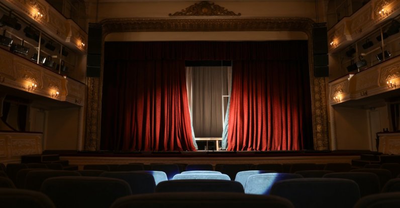A view of a theater interior with a stage and rows of seats. (Shutterstock Photo)