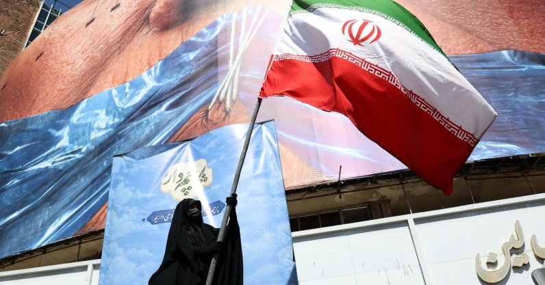 A woman holds Iran’s national flag in front of a huge anti-U.S. billboard referring to U.S. President Donald Trump and the Strait of Hormuz at Valiasr Square in Tehran, Iran, May 11, 2026. (EPA Photo)