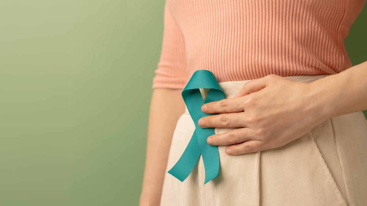 A woman holds a teal ribbon to raise awareness for ovarian cancer and PCOS. (Shutterstock Photo)
