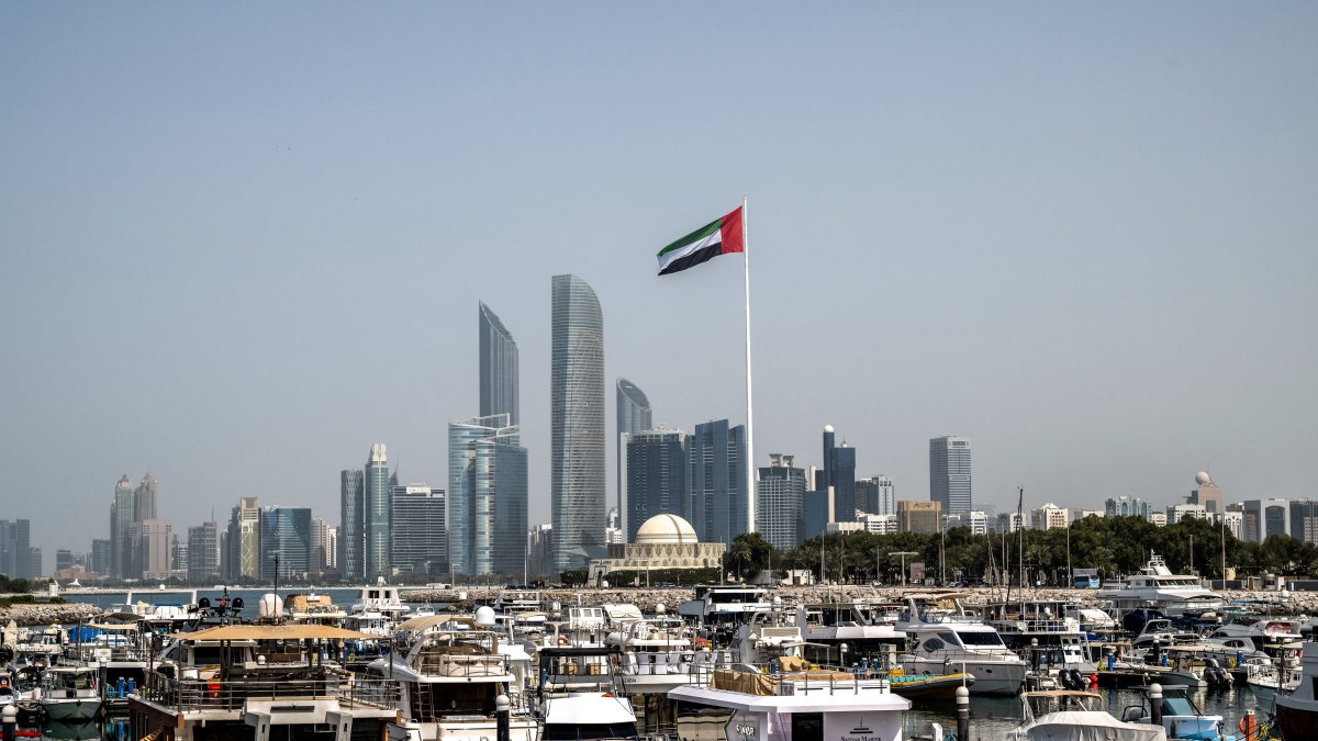 The United Arab Emirates flag flutters against the backdrop of the Abu Dhabi Skyline following a reported Iranian strike, March 1, 2026. (AFP File Photo)
