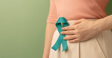 A woman holds a teal ribbon to raise awareness for ovarian cancer and PCOS. (Shutterstock Photo)