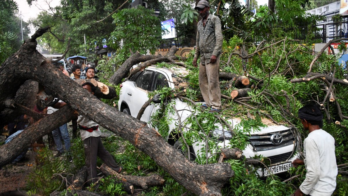 People remove a fallen tree over a car during a heavy storm,in Prayagraj, in the northern state of Uttar Pradesh, India, May 13, 2026. (Reuters Photo)