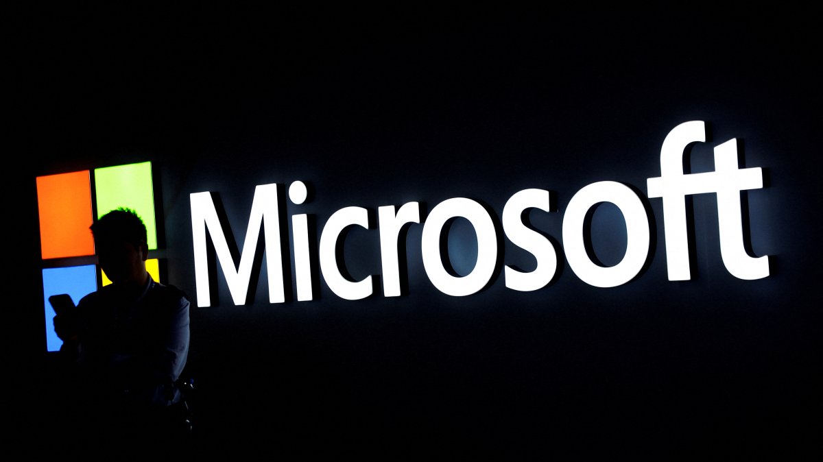 A man looks at his phone in front of the Microsoft logo during the 2025 Mobile World Congress (MWC) in Barcelona, Spain, March 3, 2025. (Reuters File Photo)