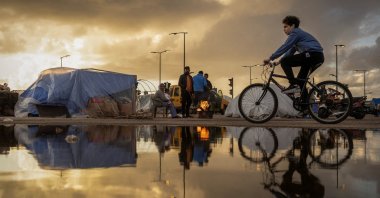 A family stand next to a fire outside their tent at a temporary encampment for displaced people, amid escalating hostilities between Israel and Hezbollah, Beirut, Lebanon, March 30, 2026. (Reuters Photo)