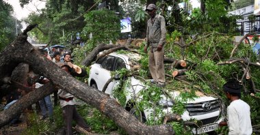People remove a fallen tree over a car during a heavy storm,in Prayagraj, in the northern state of Uttar Pradesh, India, May 13, 2026. (Reuters Photo)