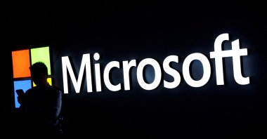 A man looks at his phone in front of the Microsoft logo during the 2025 Mobile World Congress (MWC) in Barcelona, Spain, March 3, 2025. (Reuters File Photo)