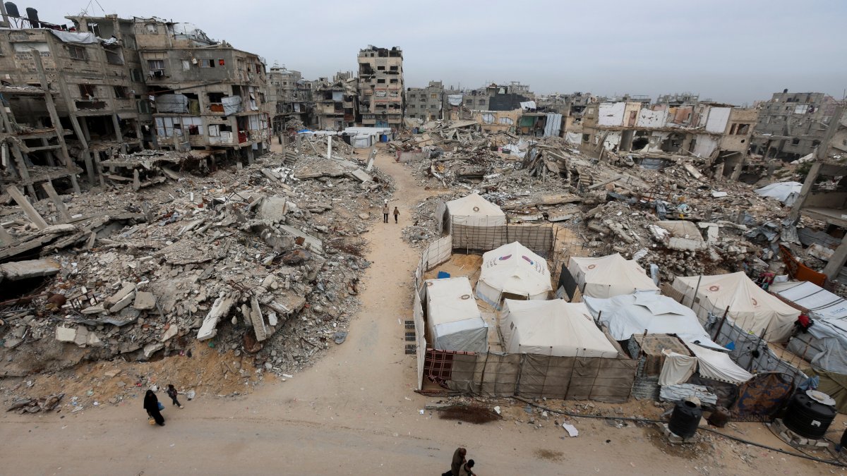 Palestinians walk past the rubble of residential buildings destroyed during the two-year Israeli attacks, in Khan Younis, southern Gaza Strip, April 15, 2026. (Reuters File Photo)