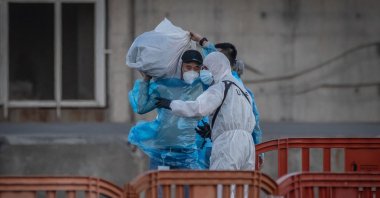 27 passengers disembark and head toward Tenerife Airport to board two flights to the Netherlands, while military and civilian personnel involved in the evacuation operation wear protective suits as a precaution against potential virus transmission, Santa Cruz de Tenerife, Spain, May 11, 2026. (Reuters Photo)