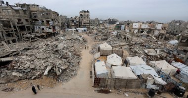 Palestinians walk past the rubble of residential buildings destroyed during the two-year Israeli attacks, in Khan Younis, southern Gaza Strip, April 15, 2026. (Reuters File Photo)