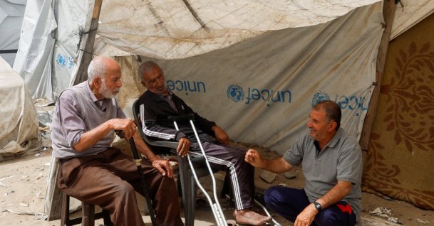 Displaced Palestinian Mustafa Al-Jazzar, 83, who fled his hometown during the 1948 Nakba, sits with friends among tents at a camp for displaced people in Khan Younis, Gaza Strip, Palestine, May 12, 2026. (Reuters Photo)