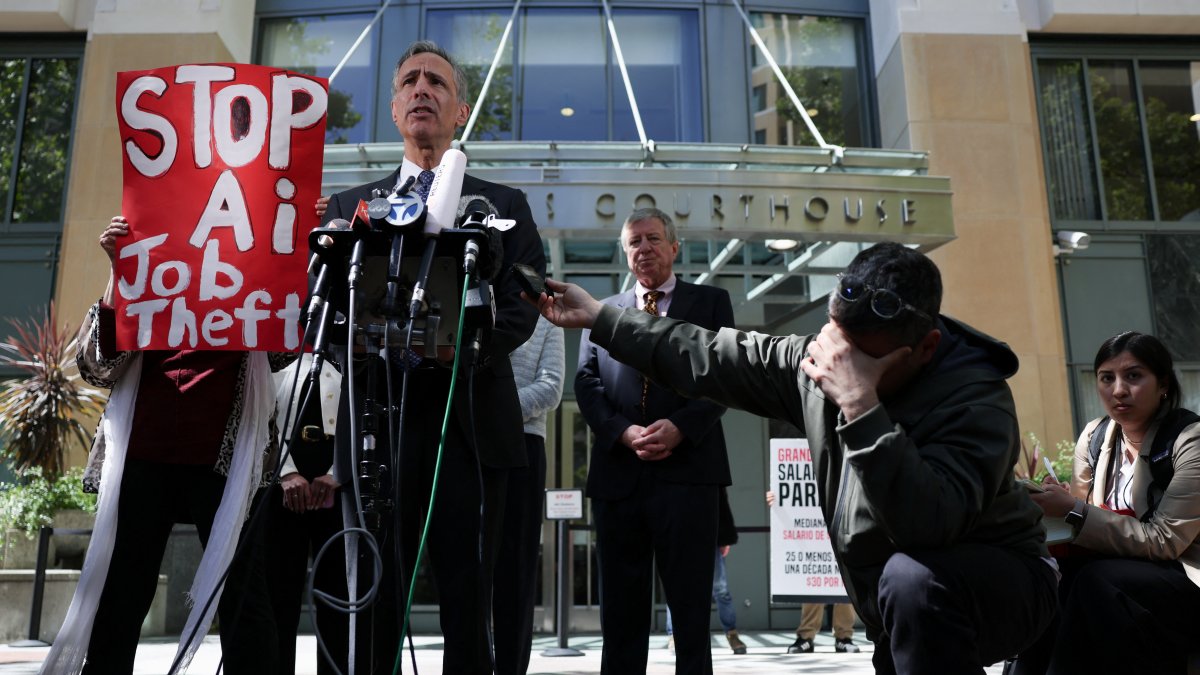 A demonstrator holds a placard as attorney William Savitt, representing OpenAI, speaks to the press outside the federal courthouse, as the trial in Elon Musk's lawsuit over OpenAI's for-profit conversion continues, in Oakland, California, U.S., May 18, 2026. (Reuters Photo)
