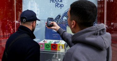People take photos through the window of the Swiss watch store Swatch to capture the new limited-edition 'Royal Pop' watches, a collaboration between Swiss watch maker Swatch and luxury brand Audemars Piguet, currently out of stock in Paris, France, May 18, 2026. (Reuters Photo)
