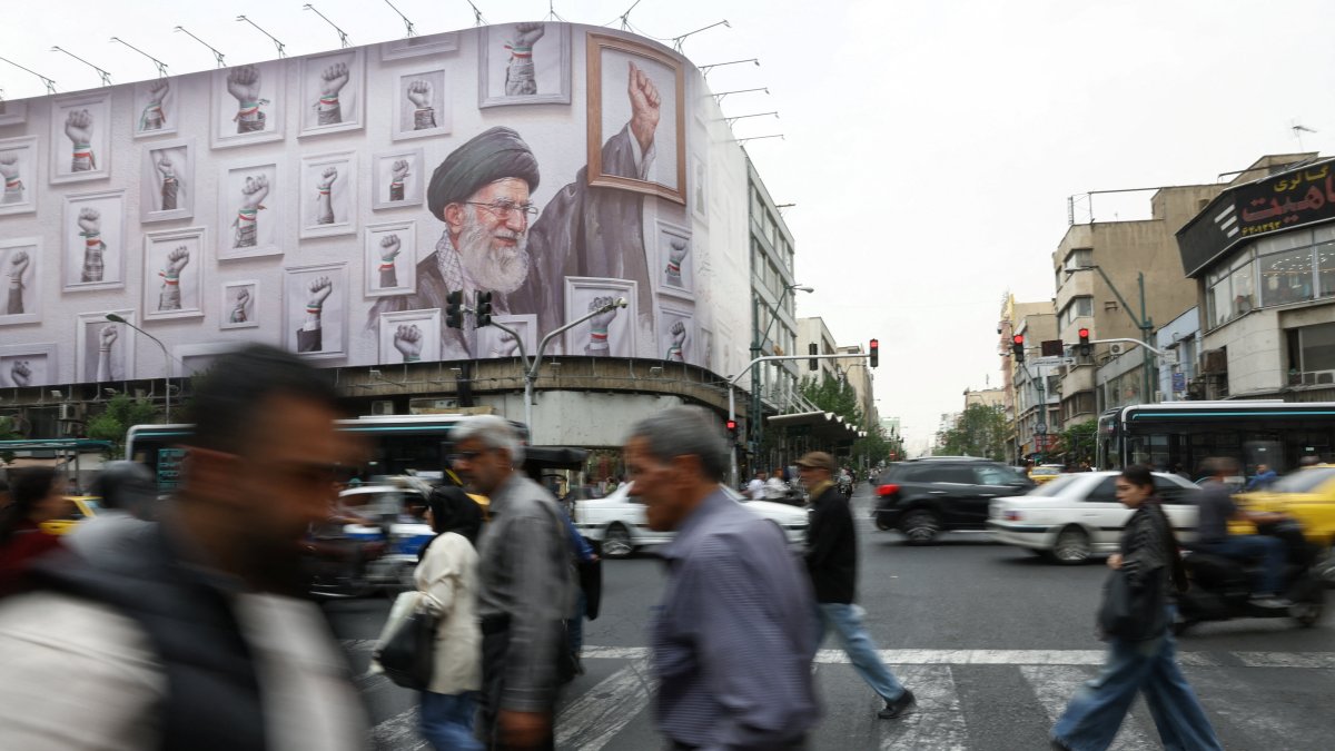 People walk near a billboard with an image of the late Iranian Supreme Leader Ayatollah Ali Khamenei, in Tehran, Iran, May 19, 2026. (WANA via Reuters)