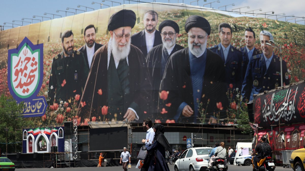 Iranians walk in front of a large billboard displaying pictures of late Iranian supreme leader Ayatollah Ali Khamenei and late Iranian president Ebrahim Raisi at the Enghelab Square in Tehran, Iran, May 21, 2026. (EPA Photo)