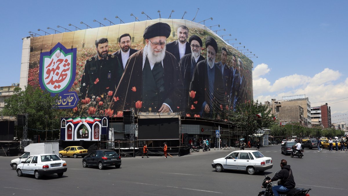 Iranians drive past a large billboard displaying pictures of the late Iranian supreme leader, Ayatollah Ali Khamenei, and the late Iranian president, Ebrahim Raisi, at Enghelab Square, Tehran, Iran, May 21, 2026. (EPA Photo)