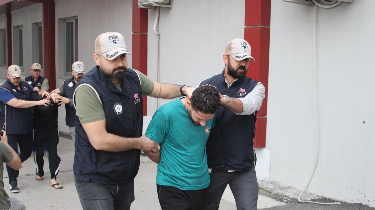 Two police officers escort a captured Daesh suspect in Adana, Türkiye, May 22, 2026. (DHA Photo)