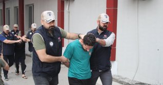 Two police officers escort a captured Daesh suspect in Adana, Türkiye, May 22, 2026. (DHA Photo)