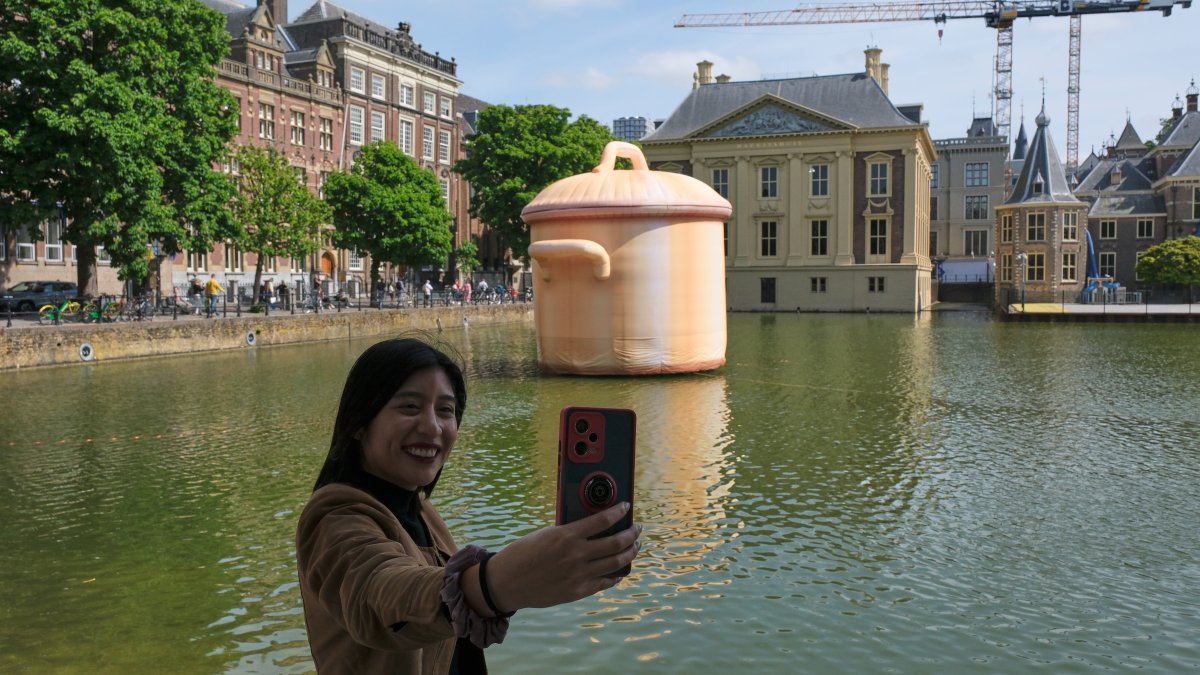 A woman takes a selfie in front of an art installation titled "Like a Pan in the Water" by Studio Job as part of the BlowUp Jubilee Art walk, The Hague, Netherlands, May 21, 2026. (AP Photo)