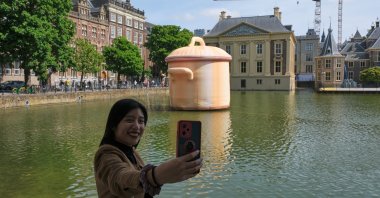 A woman takes a selfie in front of an art installation titled "Like a Pan in the Water" by Studio Job as part of the BlowUp Jubilee Art walk, The Hague, Netherlands, May 21, 2026. (AP Photo)