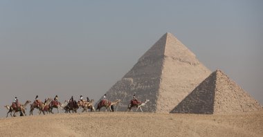 Tourists ride camels in front of the Great Pyramids plateau, Giza, Egypt, Dec. 11, 2022. (Reuters Photo)