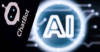 A photo shows the letters AI for Artificial Intelligence on a laptop screen (R) next to the logo of the AI Chatbot application on a smartphone screen in Frankfurt, Germany, May 13, 2026. (AFP Photo)