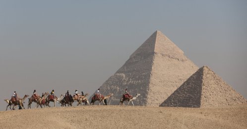 Tourists ride camels in front of the Great Pyramids plateau, Giza, Egypt, Dec. 11, 2022. (Reuters Photo)