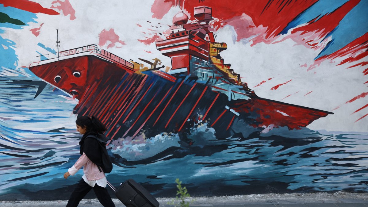 An Iranian woman walks next to a mural on a street, Tehran, Iran, May 11, 2026. (Reuters Photo)