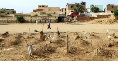 A Sudanese woman walks past graves of people killed during clashes lining the streets of Omdurman, Sudan, March 20, 2025. (AFP Photo)