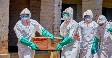 Red Cross workers wearing personal protective equipment (PPE) carry a coffin with the dead body of a child who died of Ebola, as aid agencies intensify efforts to contain a new Ebola outbreak involving the Bundibugyo strain in Mongbwalu, Djugu Territory, Ituri province, DRC, May 24, 2026. (Reuters Photo)