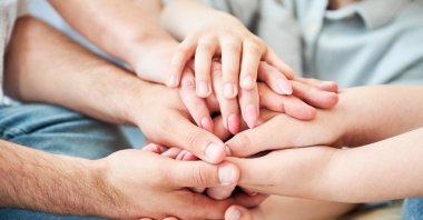 Family members place their hands together in a gesture symbolizing unity. (Shutterstock Photo)