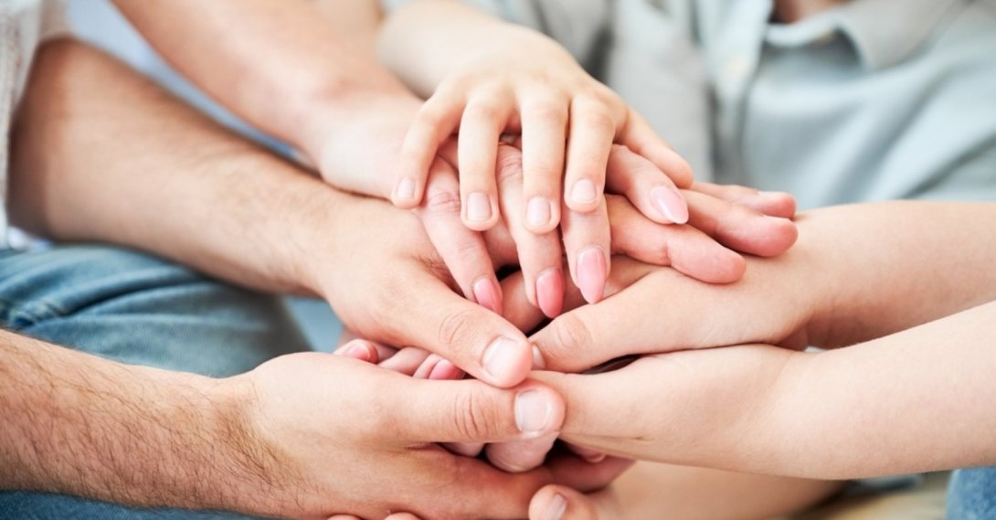 Family members place their hands together in a gesture symbolizing unity. (Shutterstock Photo)