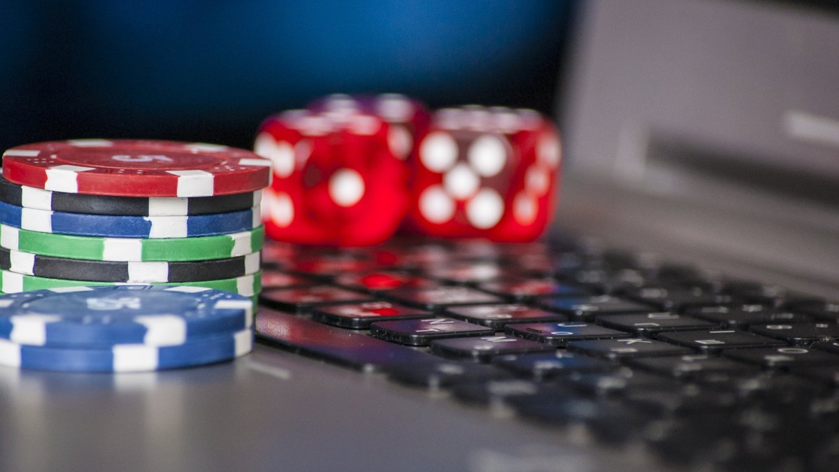 Gambling chips and dice rest on a laptop keyboard. (Shutterstock Photo)