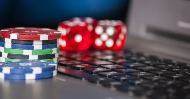 Gambling chips and dice rest on a laptop keyboard. (Shutterstock Photo)