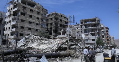 People stand in front of damaged buildings, in the town of Douma, the site of a suspected chemical weapons attack, near Damascus, Syria, April 16, 2018. (AP File Photo)