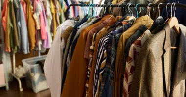 Clothing racks display assorted vintage garments hanging in a thrift shop. (Shutterstock Photo)